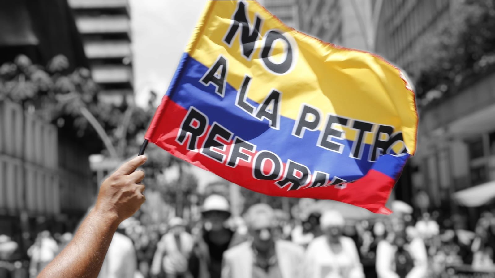 Persona sosteniendo una bandera tricolor con el lema "NO ALA PETRO REFORMA" en una marcha de protesta en blanco y negro.